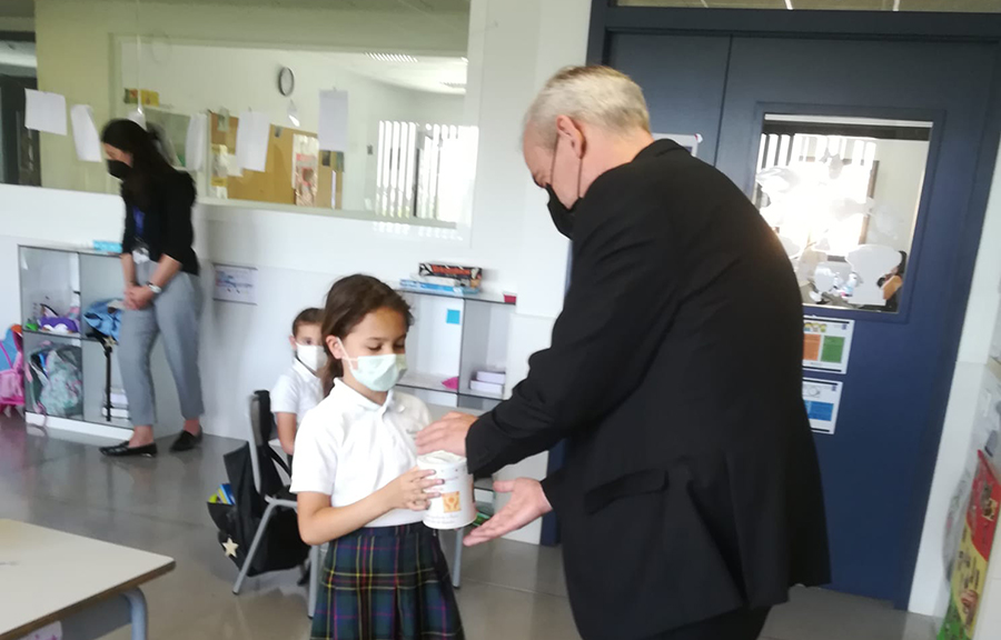 El P. Miguel Cavallé, L.C., recibe el donativo de manos de una de las niñas de la Primera Comunión